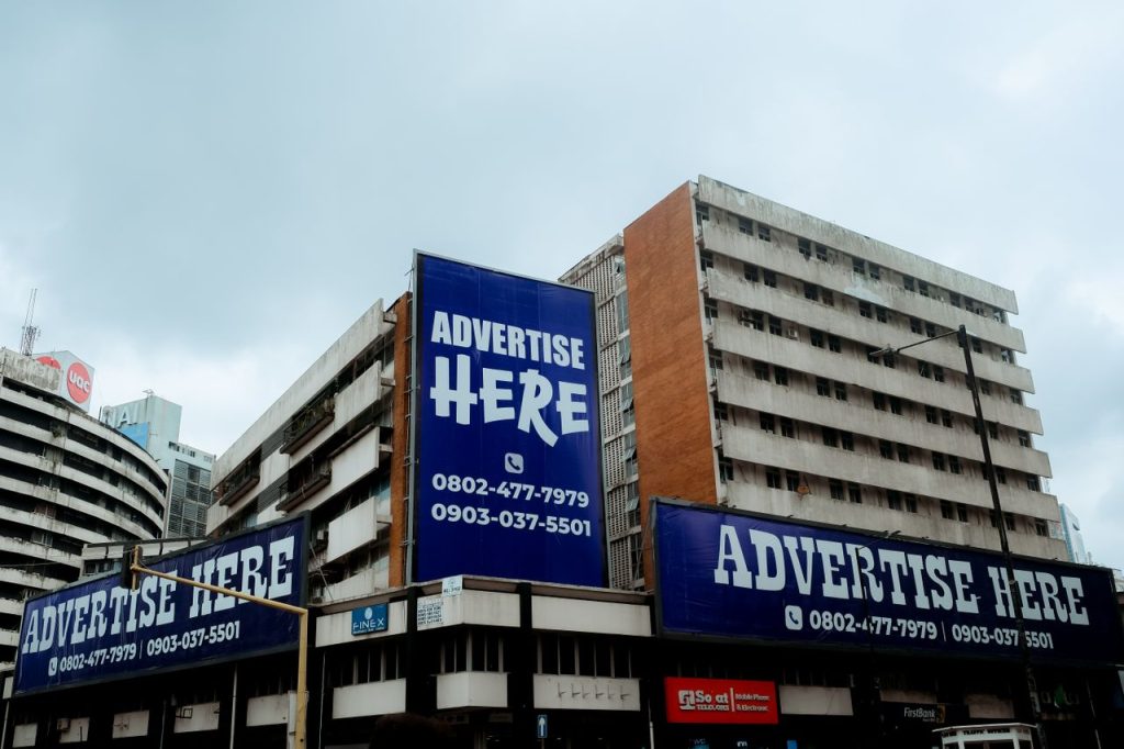 Large billboards on urban buildings displaying Advertise Here in Lagos, Nigeria.