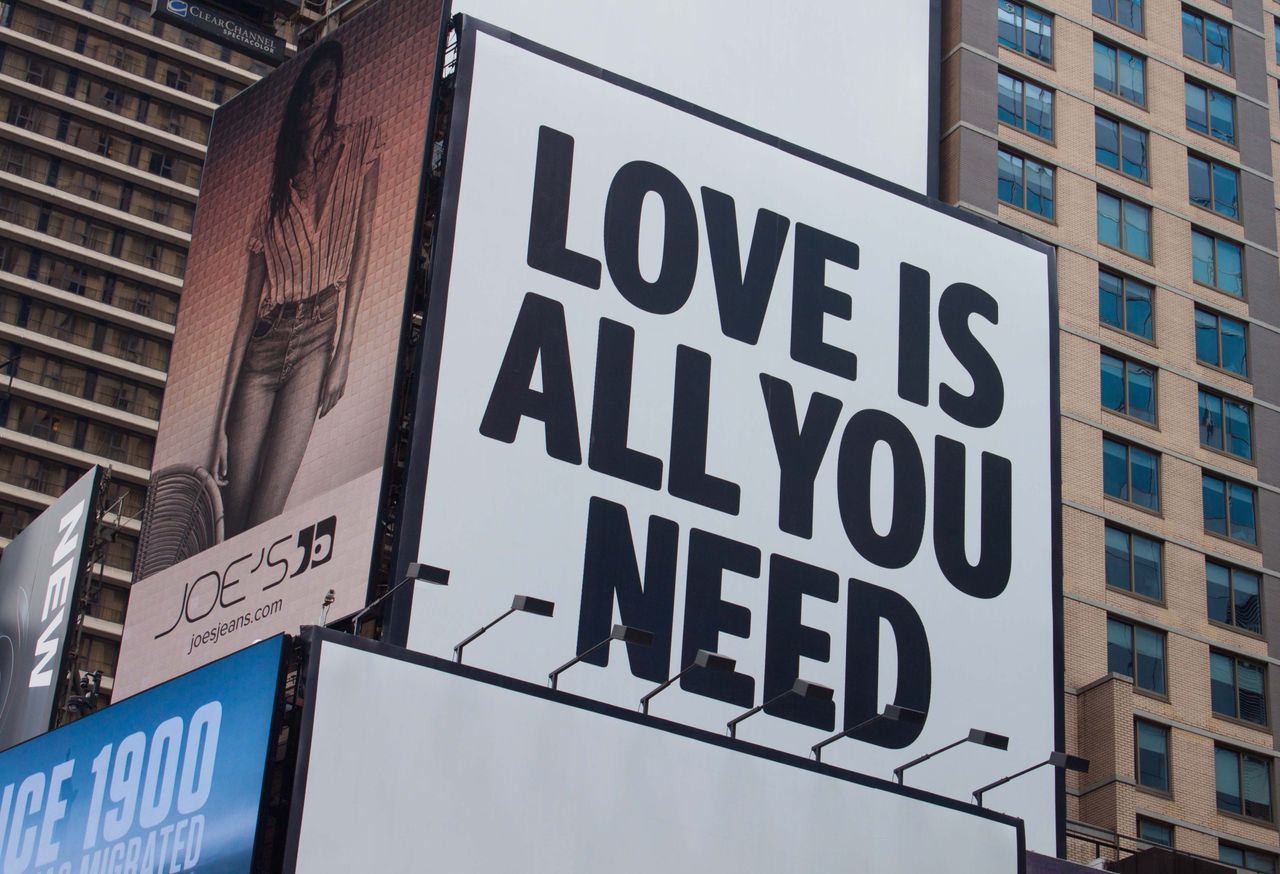 Large city billboard reads Love Is All You Need in New York City street.